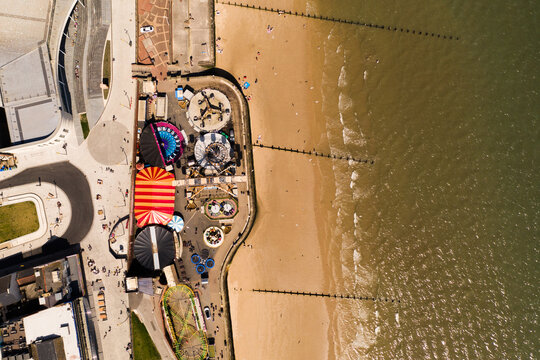 Aerial view of a seaside amusement park funfair next to a beach