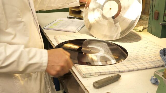 Vinyl record factory: Removing metal layer from the lacquer creating a metal stamper to press from.