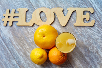 freshly squeezed juice in a glass with ice on the table and oranges the inscription # love