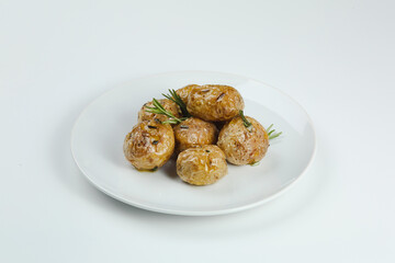 baked baby potatoe closeup on white plate. Roasted or baked baby potatoes with oil and herbs with white background