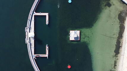 top down over art deco diving boards and swimming platforms at a bayside protected swimming lap...