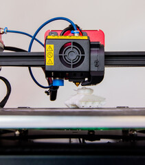 Close-up detail of 3D printer printerhead with hotend and fan. Little plastic FDM tank model. Vertical photo.