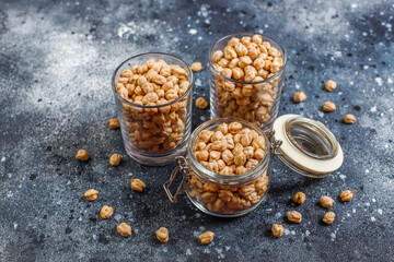 Uncooked dried chickpeas in different glass jars and bowls.