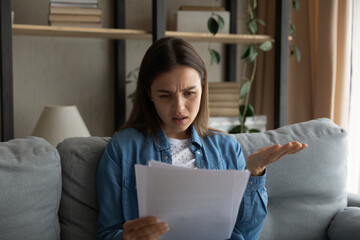 Perplexed worried woman read document feels confused due unpleasant notification from bank,...