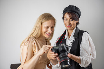 Female photographer holding digital camera and showing taken pictures to adorable model. Two women at photo studio. Photography concept.