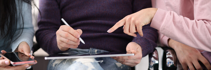 Employees point to tablet screen while discussing hot topics