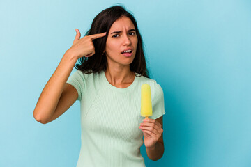 Young caucasian woman holding an ice cream isolated on blue background Young caucasian woman...