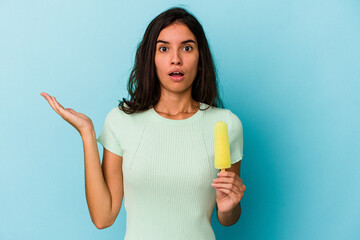 Young caucasian woman holding an ice cream isolated on blue background Young caucasian woman...