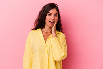 Young caucasian woman isolated on pink background shouts loud, keeps eyes opened and hands tense.