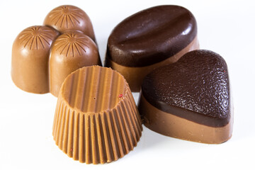 Four assorted milk chocolates, one with a heart shape, on a white background