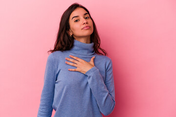 Young caucasian woman isolated on pink background taking an oath, putting hand on chest.