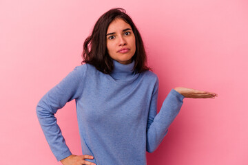 Young caucasian woman isolated on pink background showing a copy space on a palm and holding...