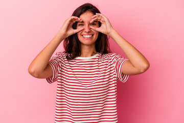 Young caucasian woman isolated on pink background showing okay sign over eyes