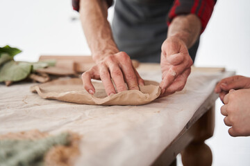 Sculptor shapes a clay plate while working at the master class for people