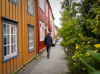 Fototapeta na wymiar Tourist on narrow street with traditional colourful wooden houses in Trondheim