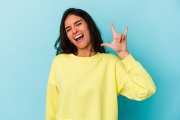 Young caucasian woman isolated on blue background showing a horns gesture as a revolution concept.