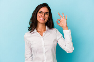 Young caucasian woman isolated on blue background cheerful and confident showing ok gesture.