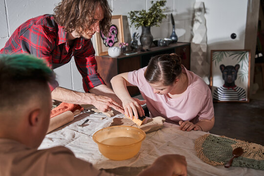 Girl with special needs listening her mentor attentively while preparing her own plate