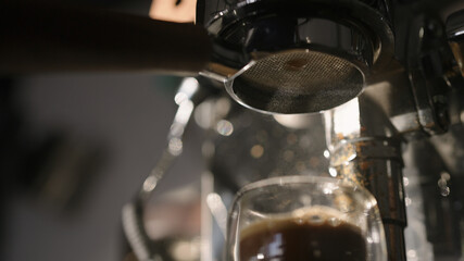 Pour espresso with bottomless portafilter into glass cup with morning light