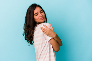 Young caucasian woman isolated on blue background hugs, smiling carefree and happy.
