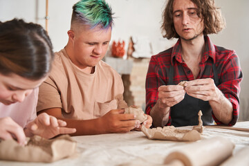 Craftsman teaching young people with special needs to make a plates from the clay