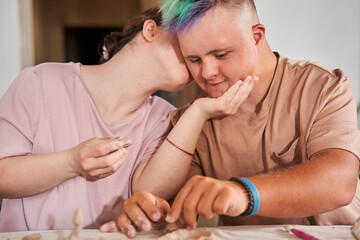 Girl with down syndrome kissing with tenderness her boyfriend after the making plates
