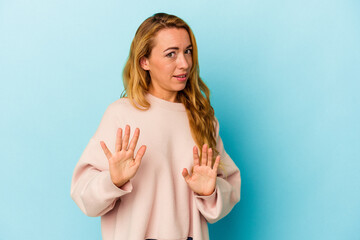 Caucasian woman isolated on blue background rejecting someone showing a gesture of disgust.