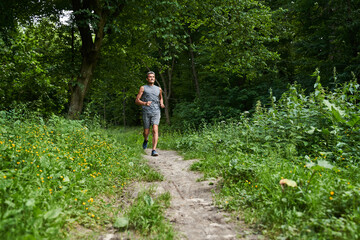 Obraz premium Man running with delight at the summer park and trying to keep body fit