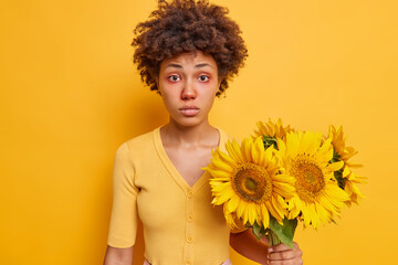 Horizontal shot of surprised curly haired Afro American woman has redness around eyesbeing allergic...