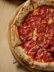 Pizza with meat pepperoni, tomato sauce, mozzarella cheese and Italian traditional spices with traditional dough and backed in oven. Copy space for restaurant menu text, selective focus.