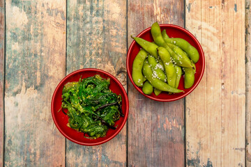 Tapas fusion of edamame in pod with sea salt and wakame salad of seaweed with sesame seeds on wooden table of a Spanish restaurant with techno-emotional cuisine