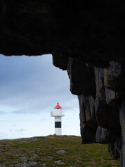 Lighthouse with rocks and cloudy sky