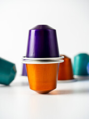 Aluminum capsules of orange and purple color with ground coffee for coffee machines stand on a white background. Pyramid of capsules. Modern methods of storing and making coffee
