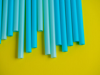 Close-up of plastic cocktail tubes of blue color on a yellow background. Top view, flat lay