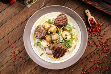 Plate of gourmet fillet mignon steaks with potatoes on a wooden background