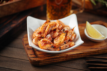 Roasted garlic shrimp appetizer with beer on wooden background