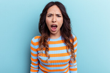 Fototapeta premium Young mexican woman isolated on blue background shouting very angry, rage concept, frustrated.