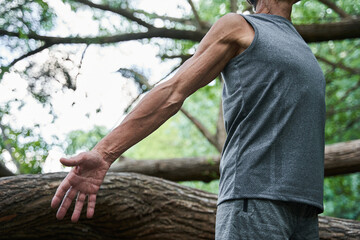 Fototapeta premium Sinewy body of the mature man with the tree trunk background