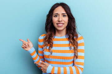 Young mexican woman isolated on blue background shocked pointing with index fingers to a copy space.