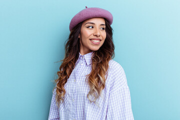 Young mexican woman isolated on blue background looks aside smiling, cheerful and pleasant.