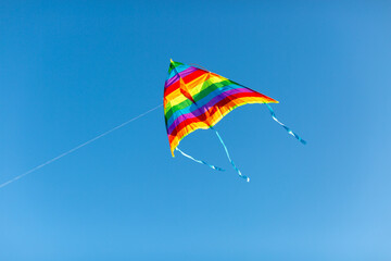 a kite in rainbow colors on a blue sky background