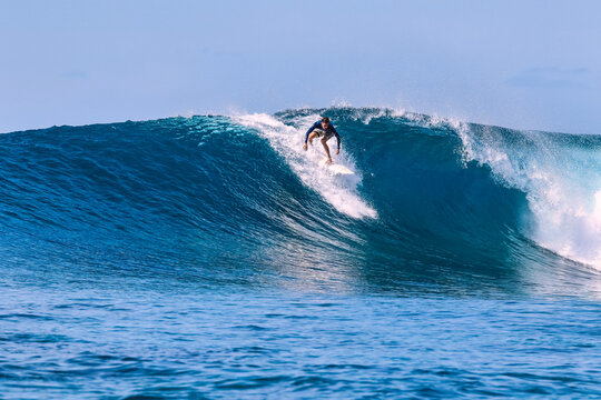 Man with surfboard surfing on sea wave against clear sky