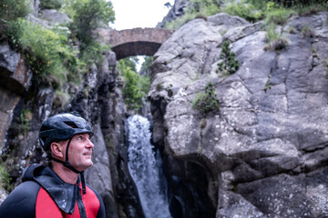 Man in a canyon under the romànic bridge With falls water