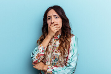 Young mexican woman isolated on blue background scared and afraid.