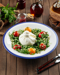 Burrata cheese arugula salad on a rustic wooden background