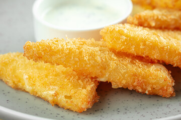Deep fried cheese triangles with sour cream sauce on a wooden background