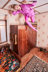 Woman in pink clothes looking away while laying upside down at the ceiling