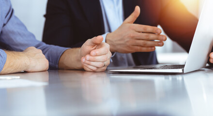 Business people using laptop computer while working together in sunny modern office. Unknown businessman with colleague at workplace. Teamwork and partnership concept