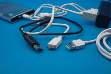 black and white USB in different type laid disorderly and mess on blue background , energy management and data transfer connector concept , selective focus on USB plug