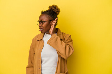 Young african american woman isolated on yellow background trying to listening a gossip.
